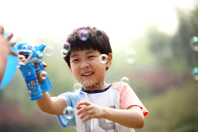 Niño haciendo burbujas de jabón al aire libre - foto de stock