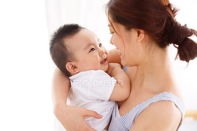 Feliz jovem mãe segurando adorável bebê em casa — Fotografia de Stock