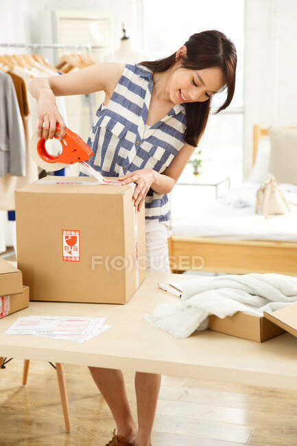 Portrait of fashion designer taping package — Stock Photo