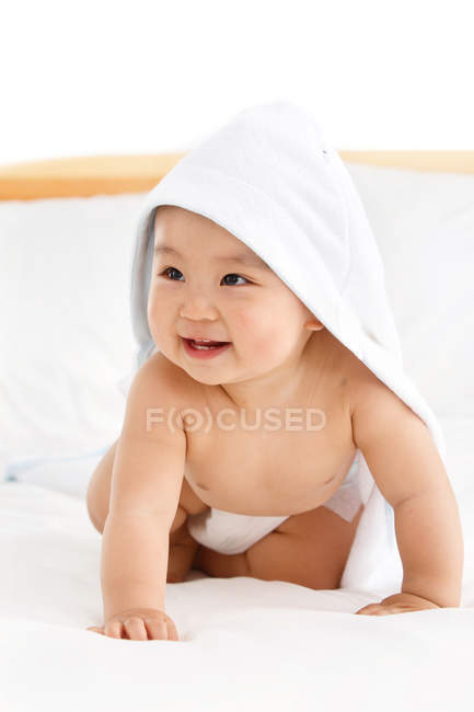 Close-up view of adorable happy chinese baby boy crawling on bed — Stock Photo