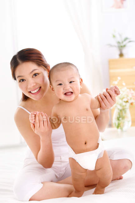 Felice giovane madre con bambino carino sorridente alla macchina fotografica — Foto stock