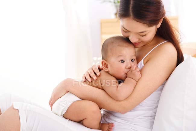 Felice giovane asiatico madre holding adorabile piccolo bambino a casa — Foto stock