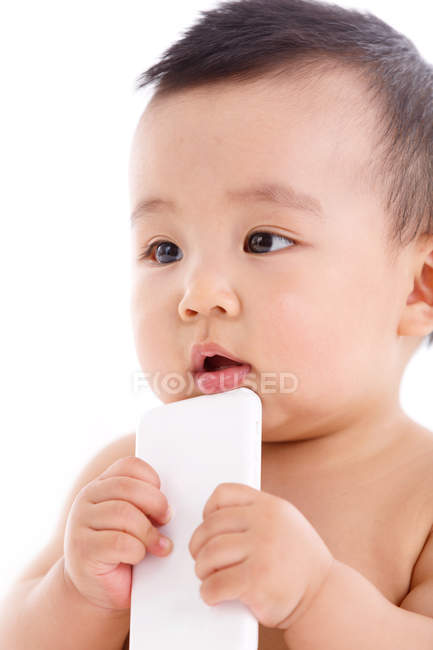 Cute asian baby boy holding smartphone and looking away — Stock Photo
