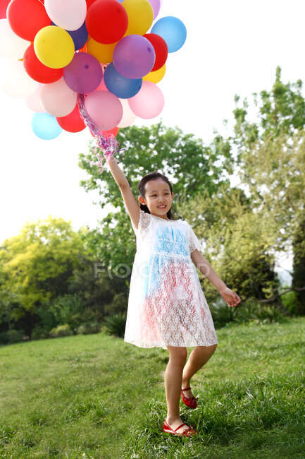 Chica sosteniendo montón de globos - foto de stock