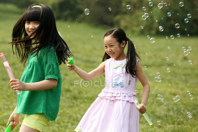 Две девушки делают мыльные пузыри на открытом воздухе — стоковое фото