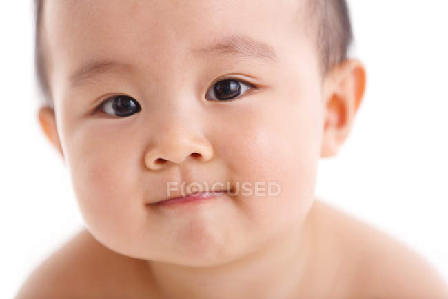Primer plano retrato de adorable asiático bebé niño mirando cámara en blanco fondo - foto de stock