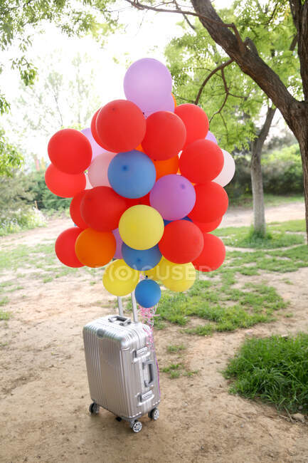 Suitcase and bunch of balloons — Stock Photo
