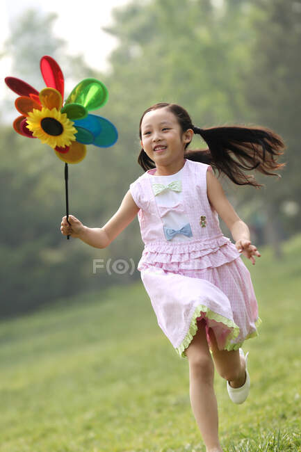Дівчинка грає з паперовим вітряком. — стокове фото
