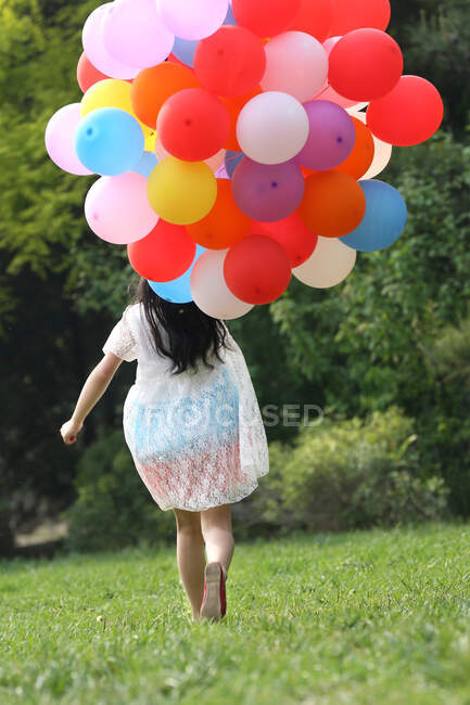 Mädchen hält Bündel Luftballons in der Hand — Stockfoto
