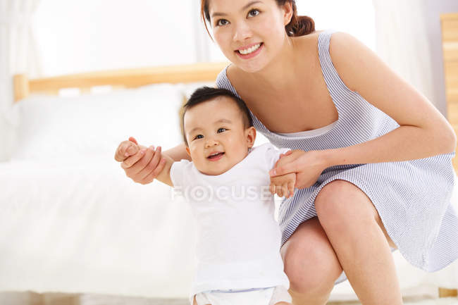 Glückliche junge Mutter mit süßem Baby lächelt in die Kamera — Stockfoto