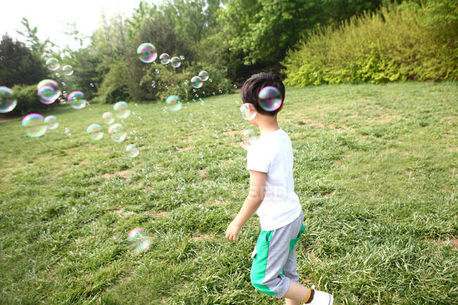 Menino fazendo bolhas de sabão ao ar livre — Fotografia de Stock