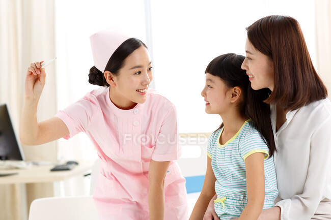 La enfermera está dando a la niña la temperatura. - foto de stock