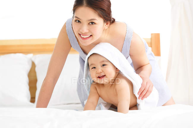 Felice giovane madre e bambino carino con asciugamano sulla testa a casa — Foto stock