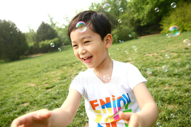 Хлопчик робить мильні бульбашки на відкритому повітрі — стокове фото