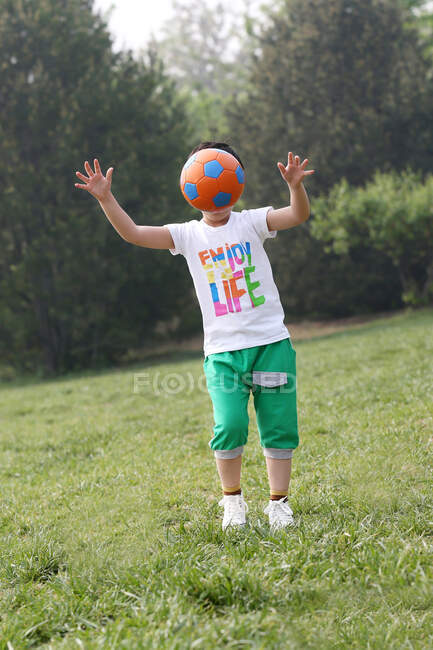 Мальчик играет в футбол в поле — стоковое фото