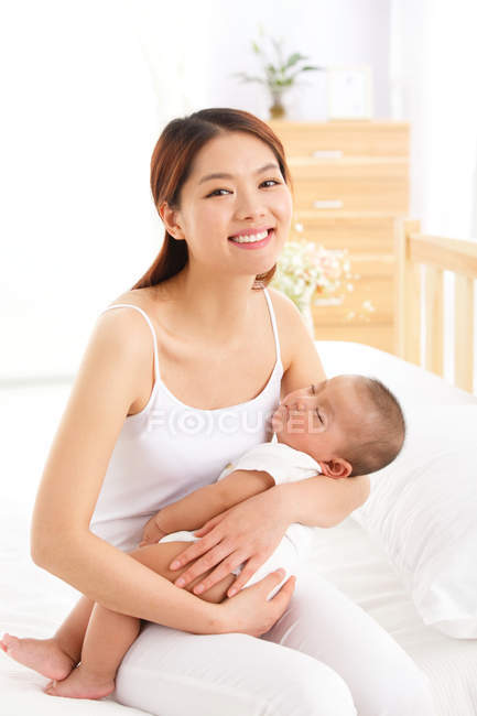 Heureux jeune asiatique mère tenant adorable petit bébé à la maison — Photo de stock
