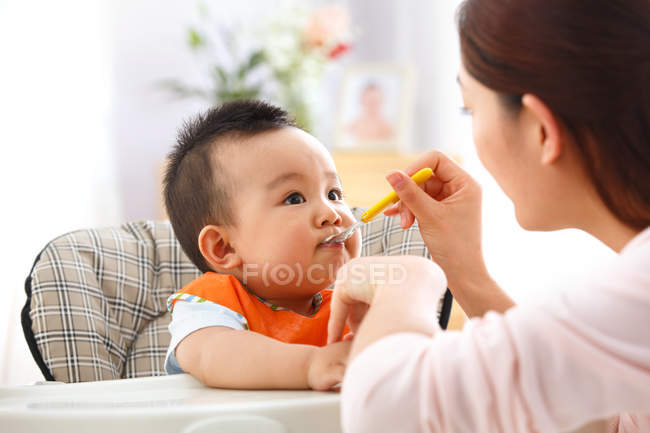 Обрізаний знімок матері тримає ложку і годує чарівну дитину — стокове фото