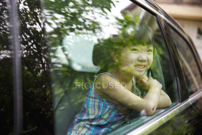 Niña feliz sentada en el coche - foto de stock