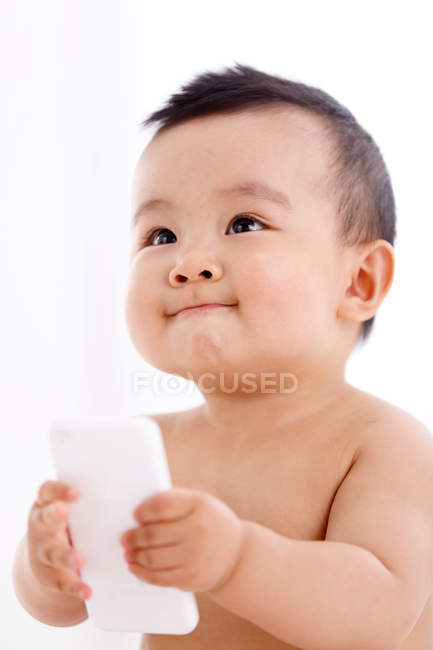 Милий азіатський хлопчик тримає смартфон і дивиться вбік — стокове фото