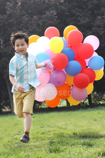 Chico sosteniendo montón de globos - foto de stock