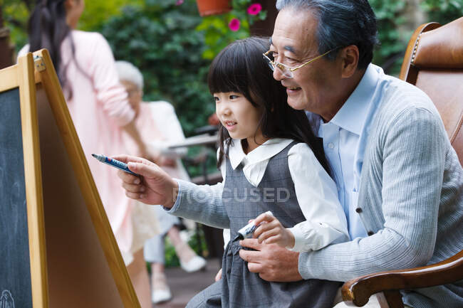 Діда навчають малюванню онуки. — стокове фото