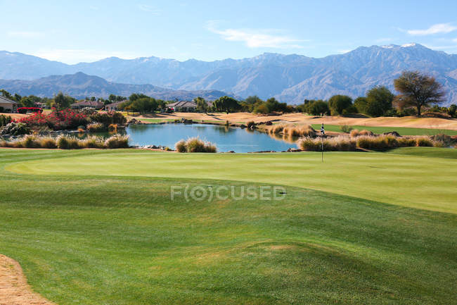Amazing green lawn at golf course and scenic mountains on horizon at sunny day — Stock Photo
