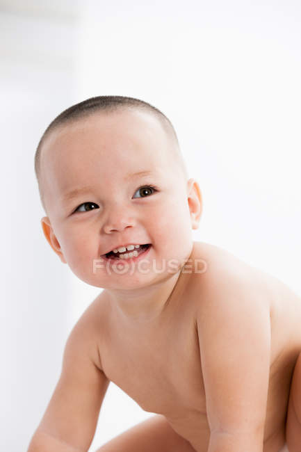 Adorable alegre bebé sentado y mirando hacia otro lado en casa - foto de stock