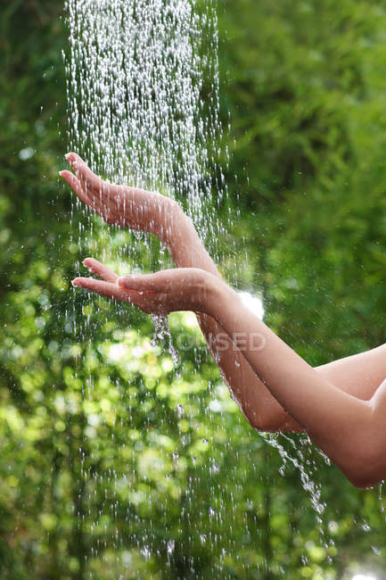 Recortado disparo de mujer joven tocando el agua y tomando ducha al aire libre - foto de stock