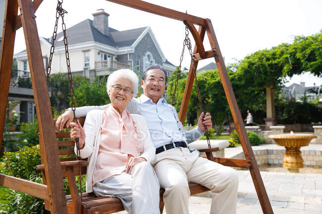 Felice vecchia coppia seduta sulla sedia a dondolo — Foto stock