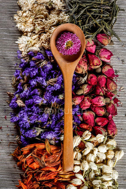 Vue de dessus de fleurs séchées, feuilles de thé et cuillère en bois sur la table — Photo de stock
