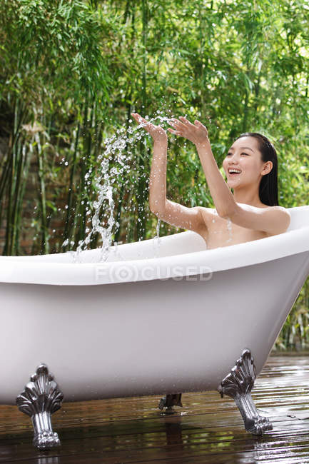Красивая улыбающаяся молодая азиатка купается в ванной на открытом воздухе — стоковое фото