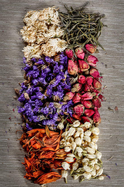Vista superior de flores secas y hojas de té en la mesa - foto de stock