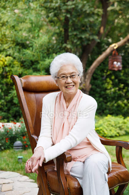 Una anciana está sentada en el jardín - foto de stock