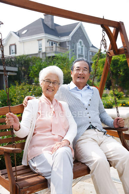 Heureux vieux couple assis dans la chaise berçante — Photo de stock