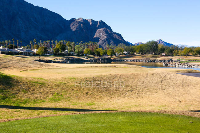 Зеленая лужайка возле озера на поле для гольфа, Монтерей, США — стоковое фото