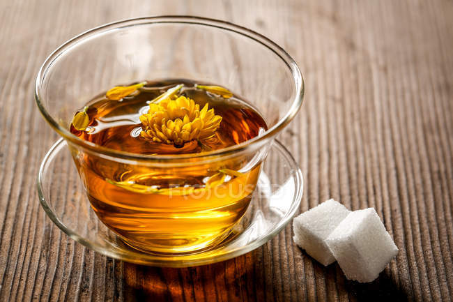 Крупный план здорового органического травяного чая в стеклянной чашке и сахара на столе — стоковое фото
