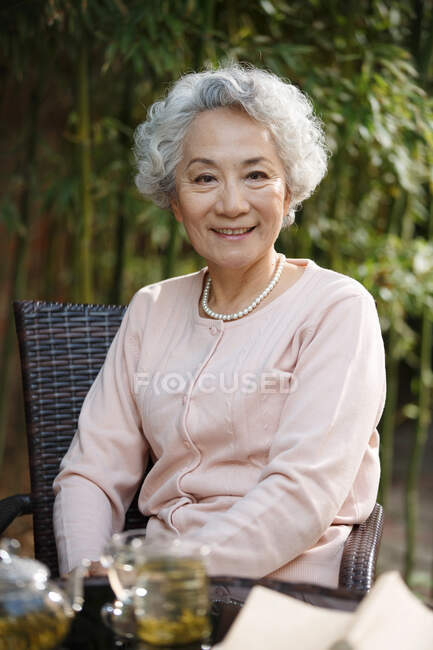 Femme âgée lisant dans la cour — Photo de stock