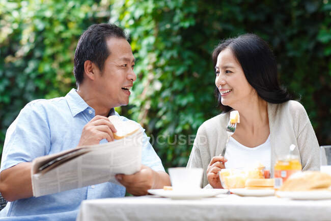 Una pareja de mediana edad está desayunando en el patio - foto de stock