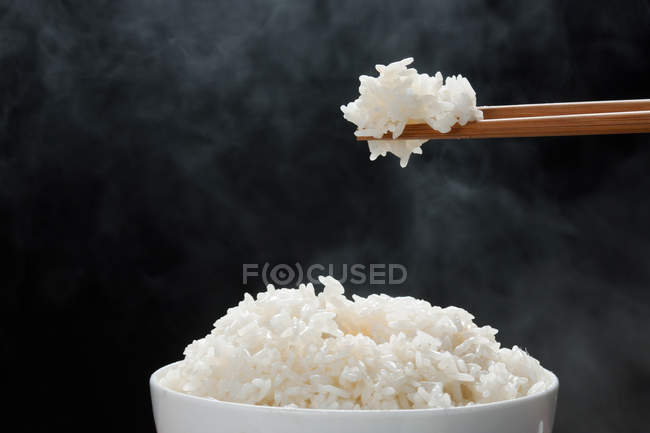 Primo piano vista di riso cotto a vapore con bacchette su sfondo nero — Foto stock