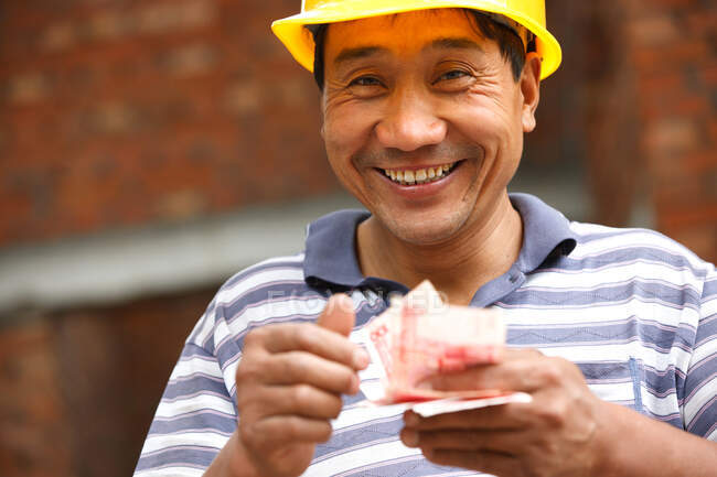 Trabalhador da construção contando papel-moeda — Fotografia de Stock