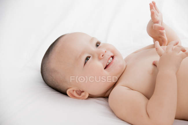 Nahaufnahme eines entzückend glücklichen Babys, das auf dem Bett liegt — Stockfoto