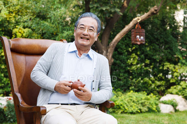 Un anciano está sentado en el jardín - foto de stock