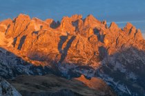 Enrosadira (alpenglow) ao nascer do sol no Pale di San Martino, Dolomitas em uma manhã de outono. O fenômeno do alpenglow é repetido dia após dia nessas rochas, que têm uma cor avermelhada, que gradualmente muda para violeta, especialmente ao amanhecer e — Fotografia de Stock
