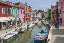 Muchos turistas caminando por las calles de Burano a lo largo del canal, pasando por las típicas casas coloridas, Burano, Venecia, Véneto, Italia - foto de stock