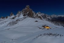 Vista clásica del paso de Giau en una noche de invierno, la Gusela de Nuvolau y la pequeña cabaña iluminada, Dolomitas, Véneto, Italia - foto de stock