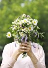 Uma jovem segurando um buquê de flores silvestres nas mãos — Fotografia de Stock