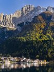 Village Alleghe en Lago di Alleghe al pie del monte Civetta, uno de los iconos de los Dolomitas del Véneto. Los Dolomitas del Véneto son parte del patrimonio mundial de la UNESCO. Europa, Europa Central, Italia, octubre - foto de stock