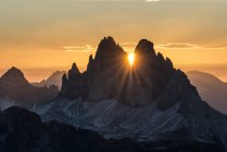 The sun rises exactly in between the crags of the Tre Cime di Lavaredo. This effect occurs only few days per year, exactly during winter solstice days, Picco di Vallandro, Prato Piazza, Dolomites, Trentino-Alto Adige, Italy — Stock Photo