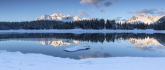 Wooden cabin surrounded by snowy peaks and woods reflected in Pal Lake at dawn, Malenco Valley, Valtellina, Lombardy, Italy, Europe — Stock Photo