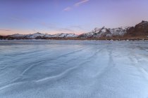 As luzes do amanhecer sobre os picos nevados em torno da superfície congelada do Lago Andossi, Vallespluga, Valtellina, Lombardia, Itália, Europa — Fotografia de Stock